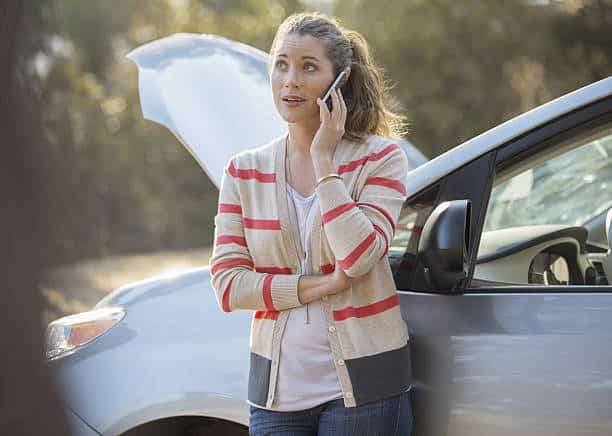 Jeune femme qui appelle une dépanneuse pour sa voiture d'occasion en panne