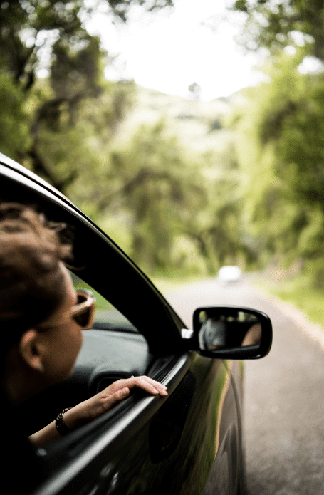 Jeune fille qui sort sa tête par la fenêtre d'une voiture