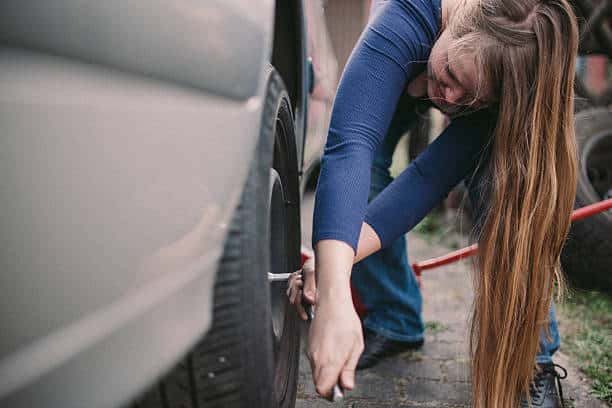 Jeune femme en train de changer ses pneus