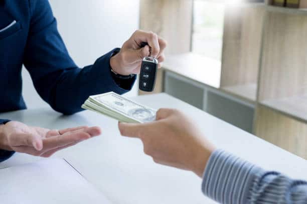 Acheteur qui conclue l'achat de sa voiture d'occasion avec un vendeur professionnel